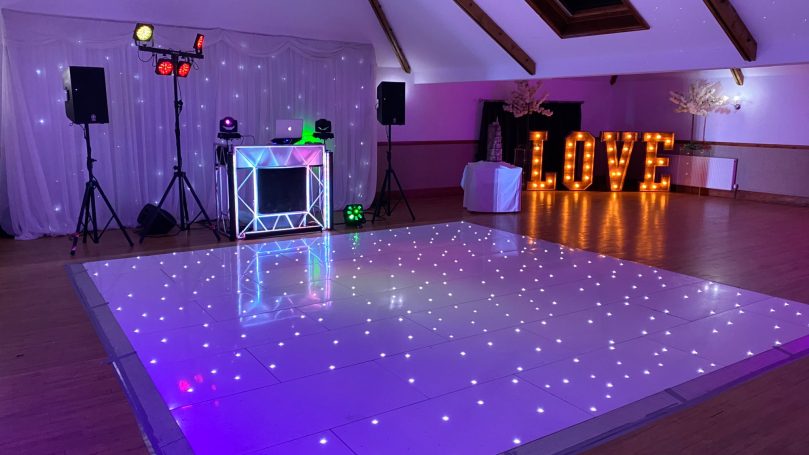 A dance floor with illuminated "LOVE" sign and vibrant lighting setup.
